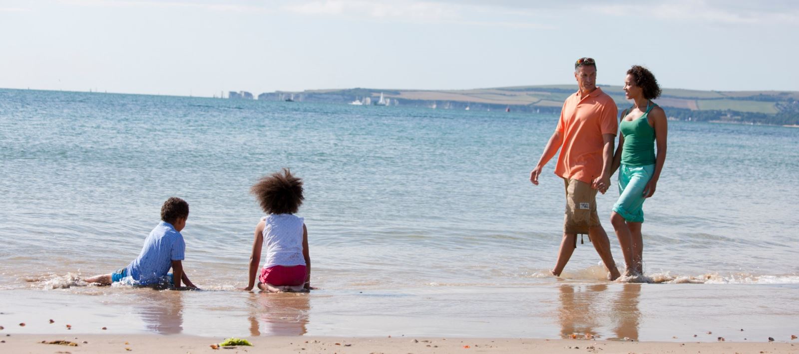 Family enjoying a dip in the sea at Sandbanks beach in Poole 